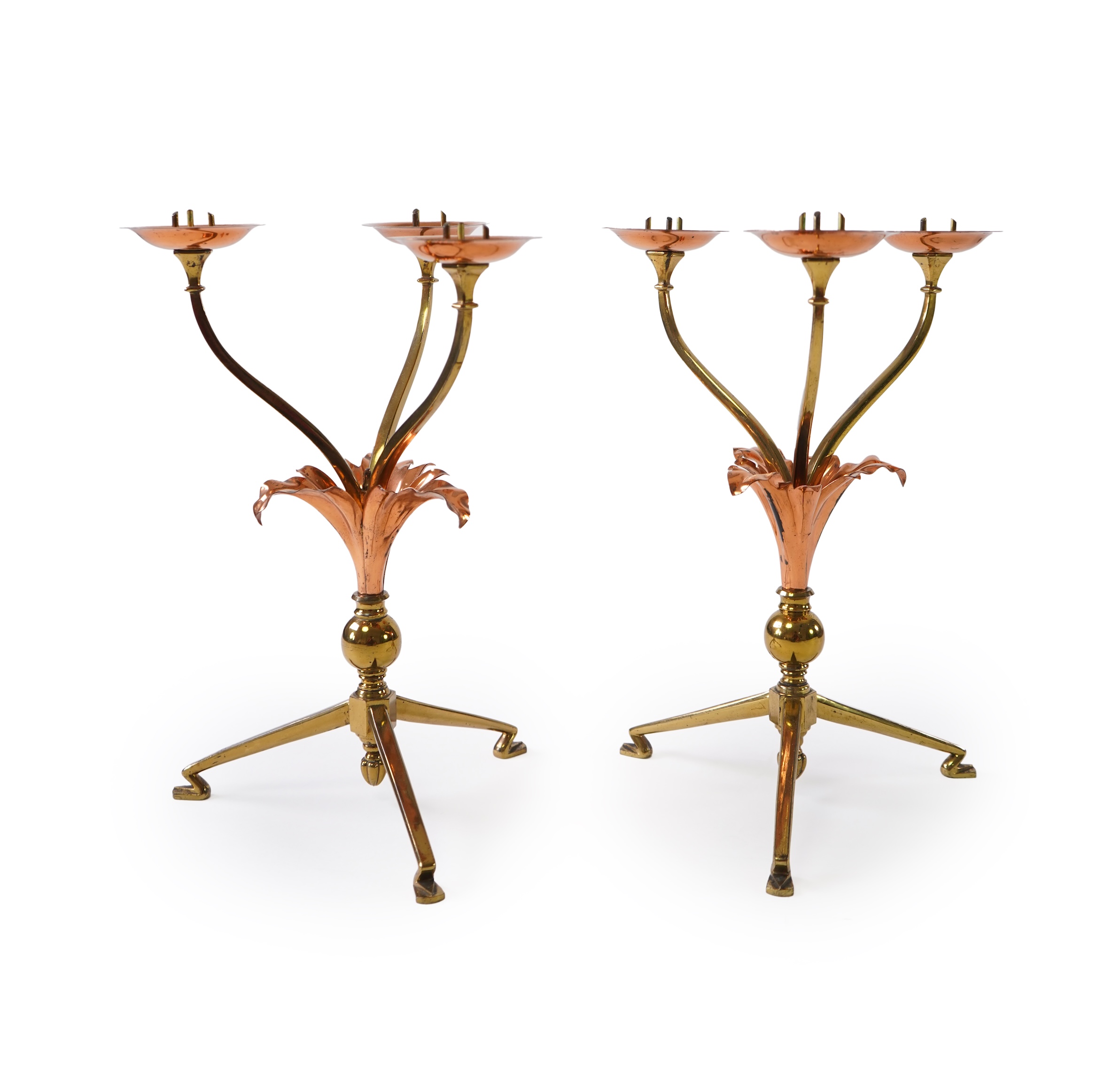 W.A.S. Benson & Co.: A pair of Arts and Crafts gilt brass and copper three branch candelabra